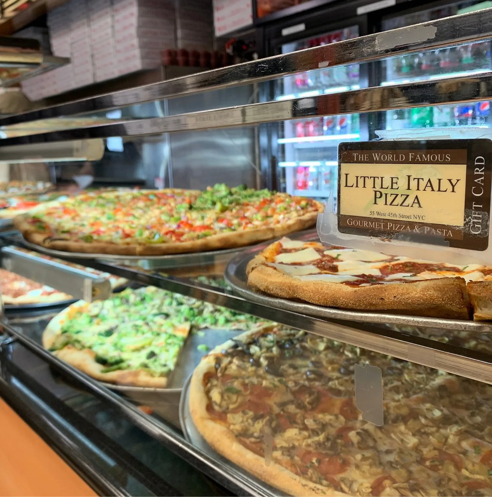 A lineup of fresh pizzas at the counter inside Little Italy Pizza on 45th