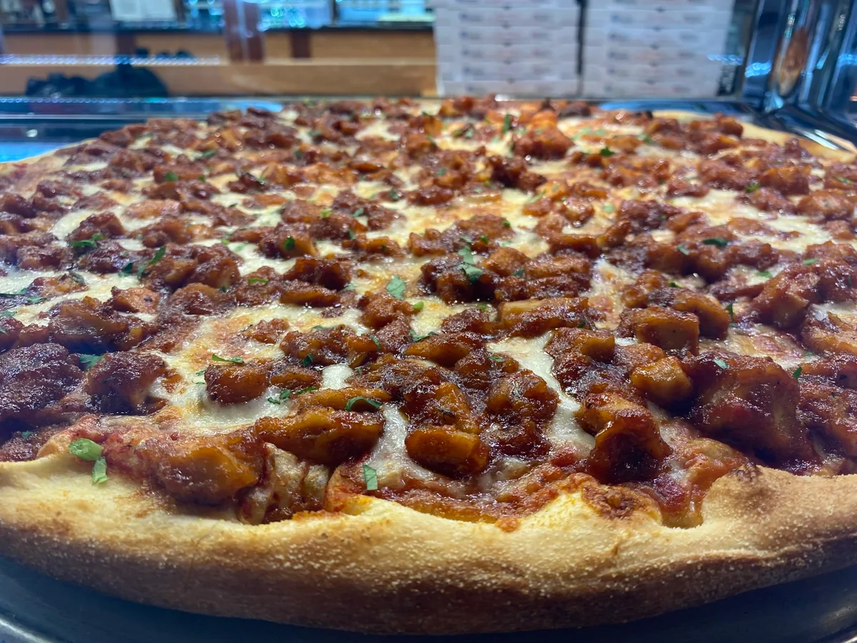 BBQ chicken pizza with melted mozzarella and fresh herbs