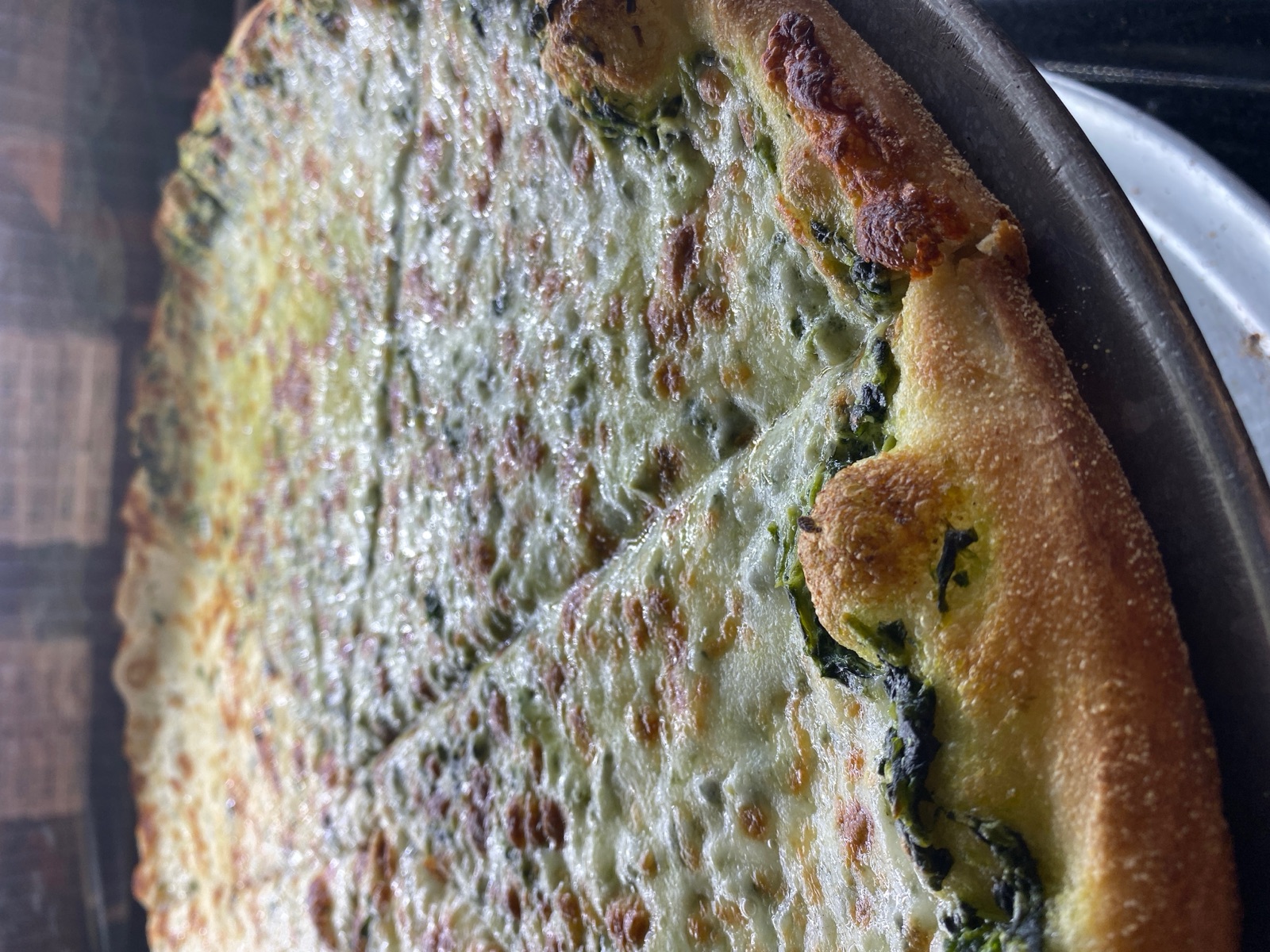 White spinach pizza with creamy melted cheese on a golden crust