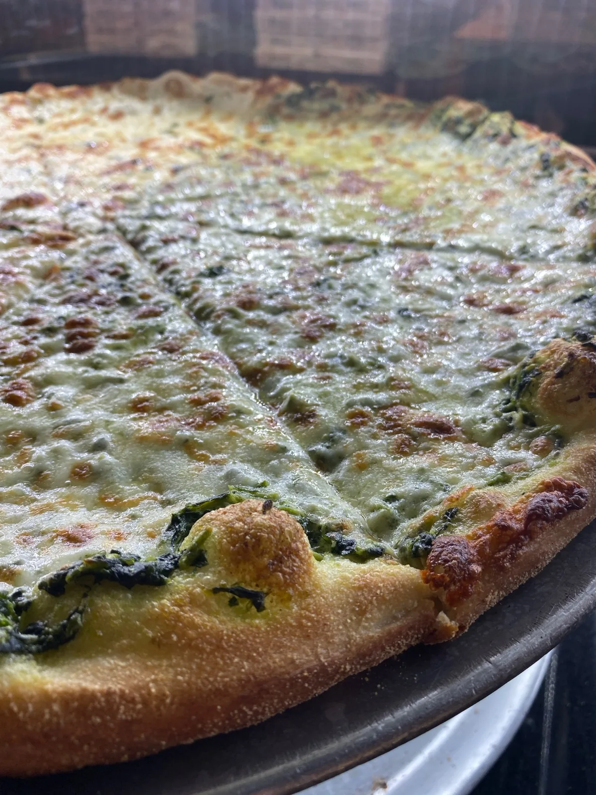White spinach pizza with creamy melted cheese on a golden crust